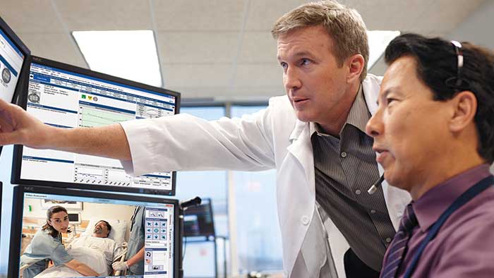Een arts en een deskundige die het telezorgprogramma van het ziekenhuis op schermen monitort