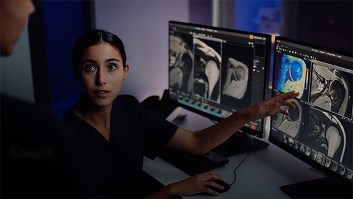 Vidéo d’une manipulatrice IRM face aux écrans de la salle de commande et montrant comment préparer les examens avant l’arrivée des patients