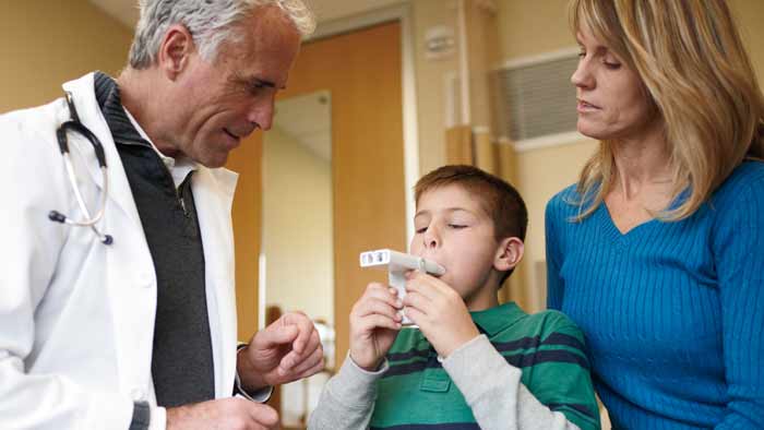 professionnel de santé aidant un enfant avec un appareil de gestion de l'asthme