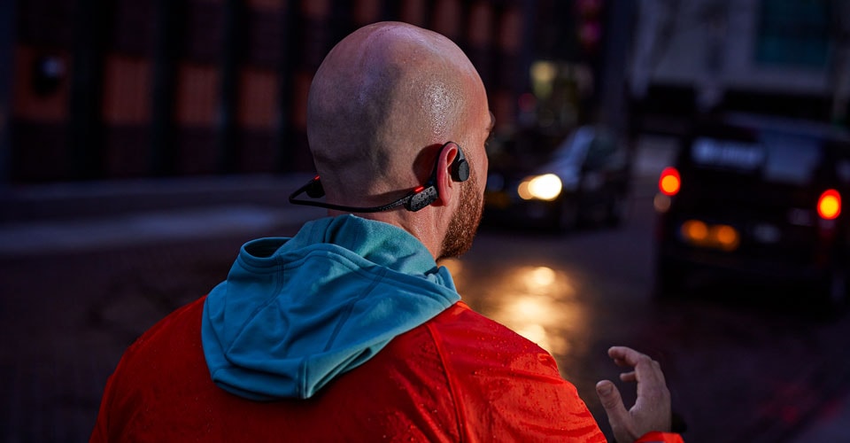 man met open oortelefoon op een drukke straat