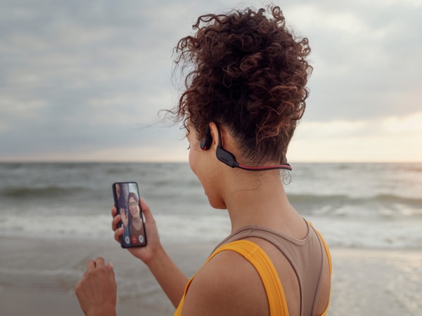 Vrouw die op een Philips-koptelefoon met bone conduction van een glashelder telefoongesprek geniet