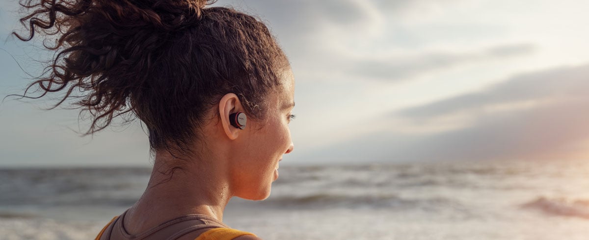 Vrouw die bij de zee true wireless-koptelefoons gebruikt