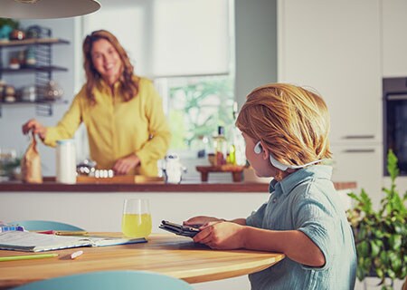 Garçon portant un casque pour enfants Philips open-ear sans fil et regardant une vidéo