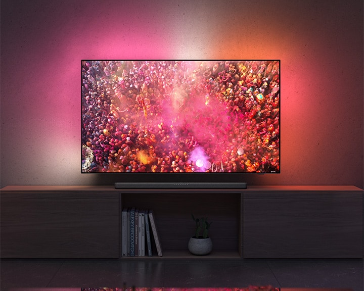 Philips TAB8200 soundbar op een houten tv-meubel onder een flatscreen-tv met Ambilight