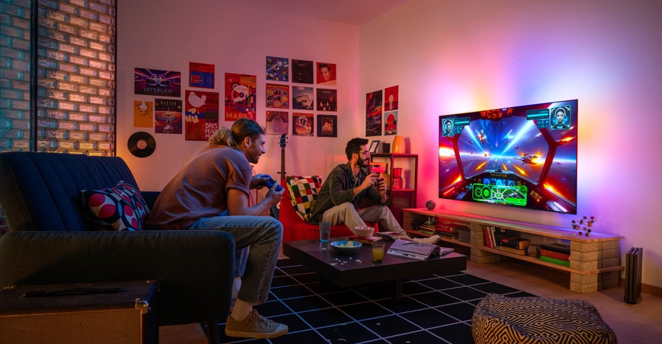 Twee mensen spelen enthousiast een ruimtethema-videogame in een gezellige, kleurrijke woonkamer