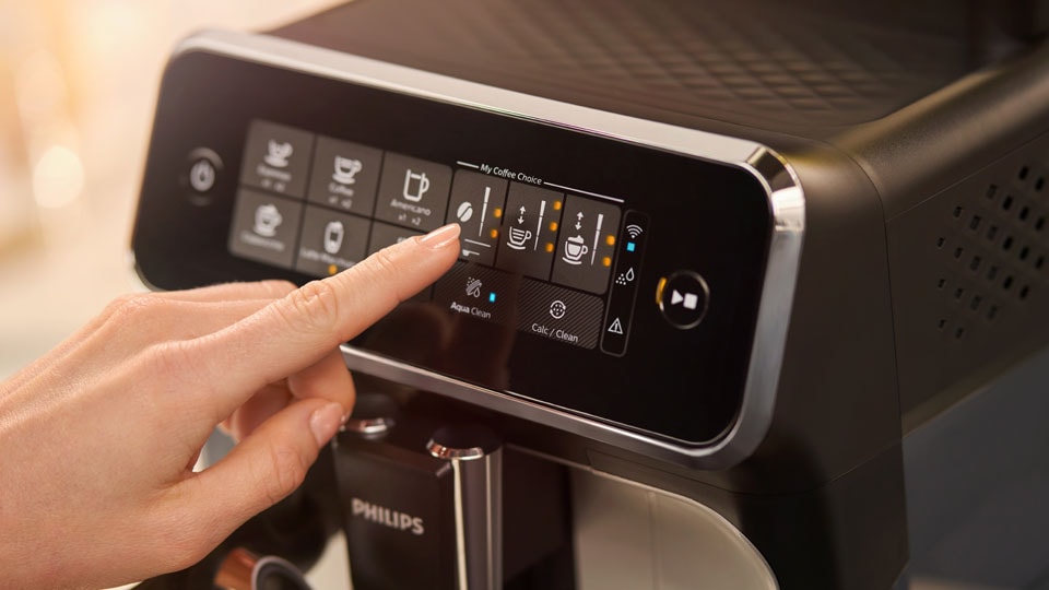 Doigt sélectionnant une option sur une machine à café automatique.