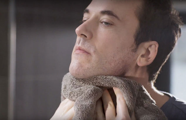 Een man met lichte stoppels en bruin haar houdt een bruine handdoek tegen zijn nek.