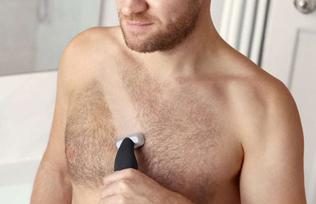 Close-up van de behaarde borst van een man met die een Philips OneBlade vasthoudt.