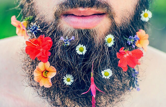 Close-up van de baard van een man waar veel verschillende en kleurrijke bloemen aan zijn toegevoegd.