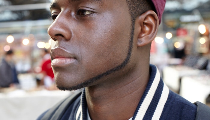 Man met pet met een strook gezichtshaar van 1 cm rond de rand van het gezicht van kaaklijn tot kaaklijn.